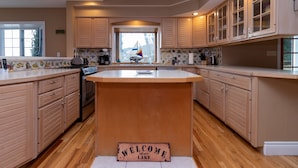 Una cocina con armarios de madera, una isla central y un cartel de bienvenida.