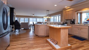 Una cocina amplia con suelo de madera, una isla central y un ventanal con vistas al exterior.