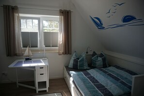 Relax in a serene bedroom with a neatly made bed, a desk, and a window with a view.