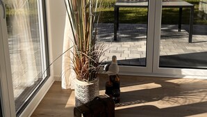 A modern interior with large windows, a potted plant, and a wooden bench.