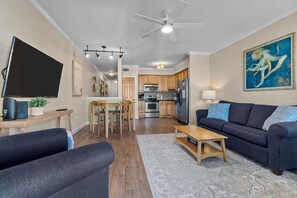 A modern living room with a dark sofa, a wooden coffee table, and a TV on a stand. - FFR202 Atlantic Splash by First Flight Rentals (Kill Devil Hills)