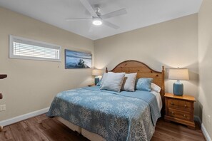 A bedroom with a wooden bed, a nightstand, a ceiling fan, and a window with blinds.