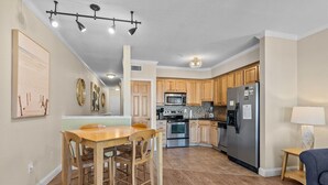 A modern kitchen with wooden cabinets, stainless steel appliances, and a dining area with a wooden table and chairs.