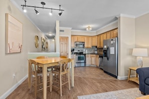 A modern kitchen with wooden cabinets, stainless steel appliances, and a dining area with a wooden table and chairs.