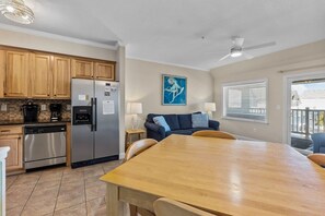 A modern kitchen with wooden cabinets, stainless steel appliances, and a dining area with a wooden table and chairs.