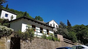 Un edificio su due piani con facciata bianca, una base in pietra e una scala in legno che conduce all'ingresso.