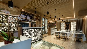 Un restaurante moderno con techo de madera, divisiones de vidrio y una zona central con mesas y sillas.