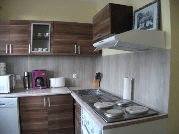 A compact kitchen with wooden cabinets, a microwave, a coffee maker, and a stove.