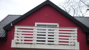 A red building with a white balcony and a black roof.