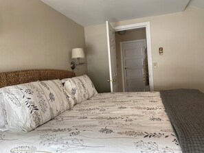 Cozy retreat with a patterned bedspread and a comfortable bed, featuring a wall-mounted lamp and a unique wall decoration.