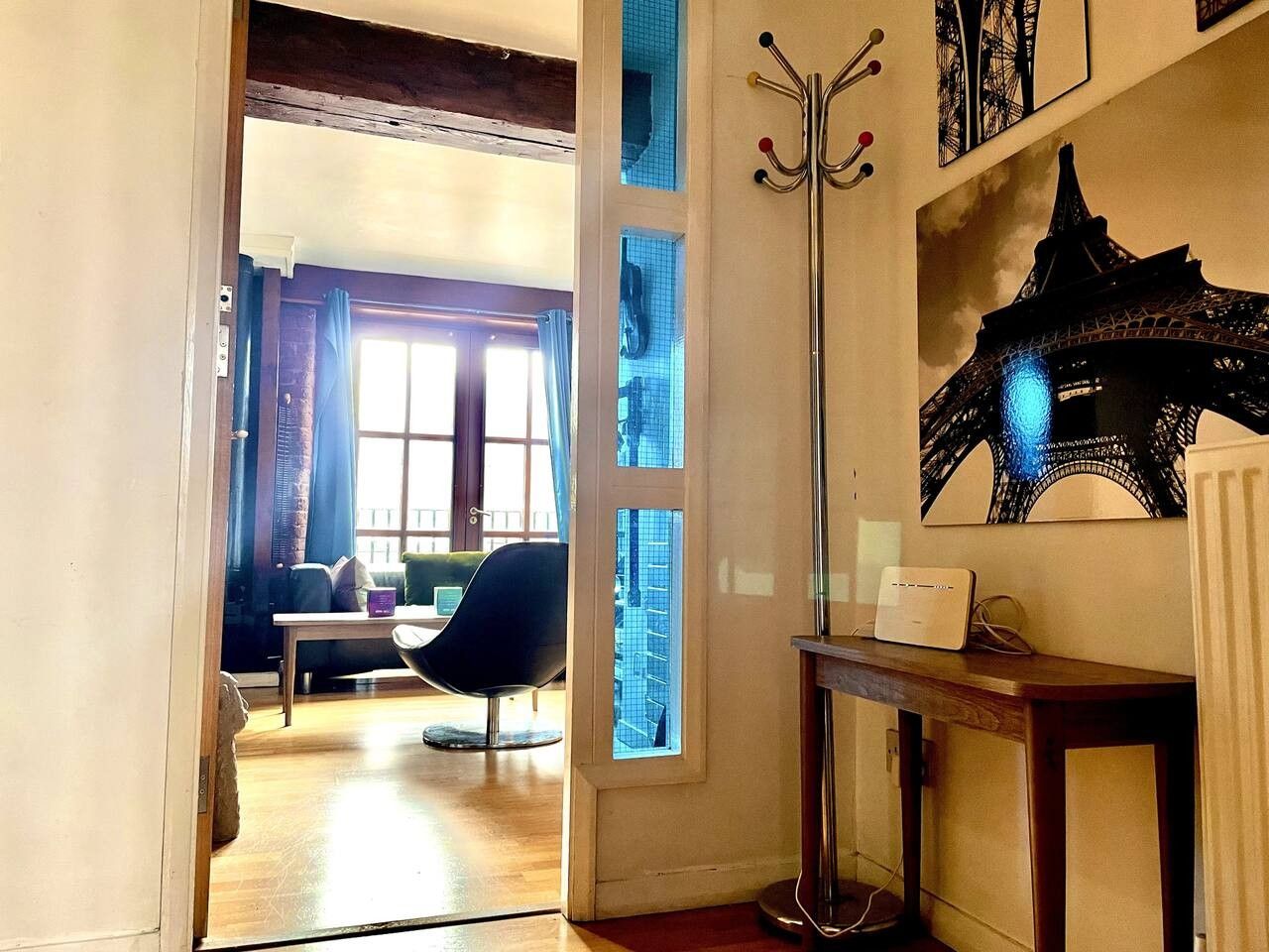 Ein Zimmer mit Holzboden, einem schwarzen Stuhl, einem Tisch mit einem weißen Gerät und einem Fenster mit blauer Glasbeschichtung.