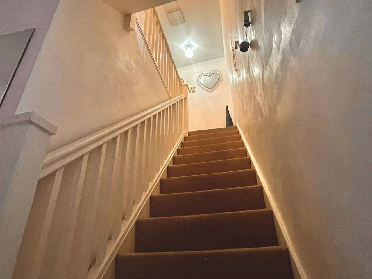 A staircase with wooden steps and white railings leading to a landing.