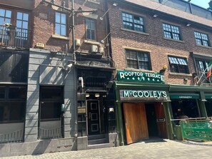 A building with a green awning labeled 'McCool's' and a sign for 'Rooftop Terrace.' - Mathew Street Penthouse 2 bed sleeps 4 (Liverpool)