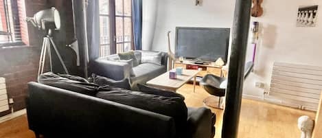 Una sala de estar con un sofá, un televisor y una lámpara.