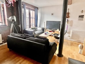 A living room with a sofa, a television, and a lamp. - Mathew Street Penthouse 2 bed sleeps 4 (Liverpool)
