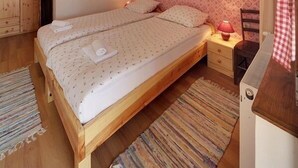 Un dormitorio con cama de madera, una mesita de noche, una lámpara, un papel tapiz con diseño y una puerta al baño.