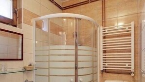 Un baño con ducha de vidrio, inodoro y lavamanos.
