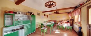 A dining area with green furniture, a wooden ceiling, and a rustic decor. - Sobe Kod Baje - Baranjska Kuca (Bilje)