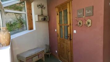 A cozy room with a wooden bench, a window with a view, a wooden door, and wall decorations.