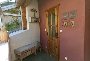 A cozy room with a wooden bench, a window with a view, a wooden door, and wall decorations. - Charmante Ancienne Maison de Vignerons (Valserres)