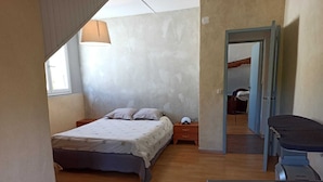 Ein Schlafzimmer mit Bett, Nachttisch, Lampe und Schreibtisch mit Stuhl.