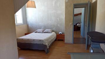 A bedroom with a bed, bedside table, lamp, and a desk with a chair.