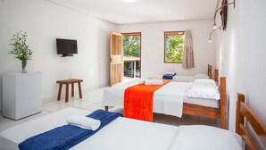 Une chambre d’hôtel avec deux lits, une télévision, une petite table et une plante.