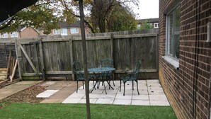 A patio with a table and chairs, a wooden fence, and a grassy area. - Sunny City (Peterborough)