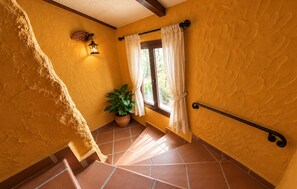 Un escalier avec une rampe, une plante en pot et une fenêtre avec des rideaux.