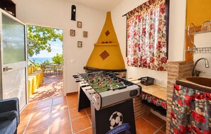 Une pièce avec une table de baby-foot, un four en briques et une vue sur la mer.
