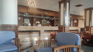 A hotel registration area with a reception desk, wooden chairs, and a polished marble floor. - Hotel Stern Pattaya (Pattaya)