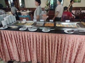 A buffet setup with various food items and serving utensils.
