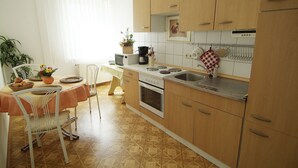 A kitchen with wooden cabinets, a stove, a sink, and a dining area with a table and chairs.