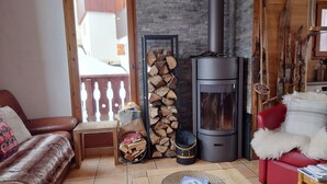 Una sala de estar acogedora con chimenea, un sofá de cuero rojo, una mesa de centro de madera y un sillón rojo.