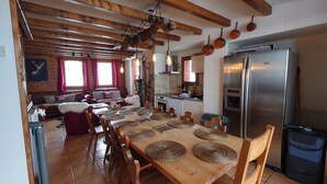 Una cocina acogedora con una mesa de comedor de madera, sillas y un refrigerador de acero inoxidable.
