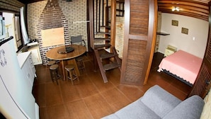 A compact room with a dining area, a bed, and a staircase. - Pousada Vento & Cia (Laguna)