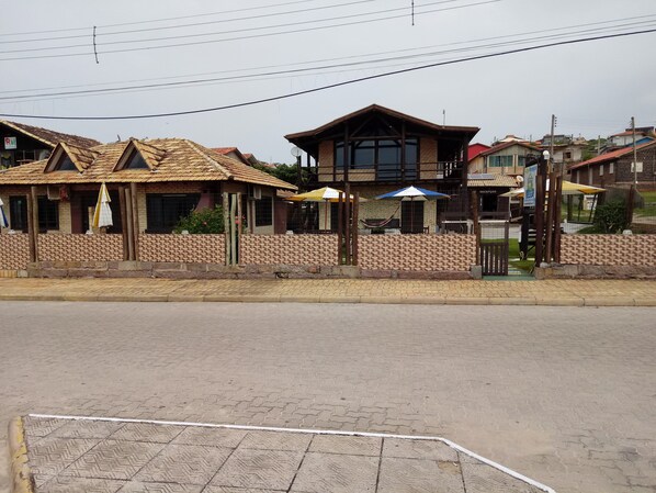 A building with a tiled roof, a brick wall, and a gated entrance. - Pousada Vento & Cia (Laguna)