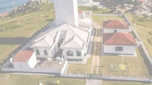 An aerial view of a coastal property with a central building surrounded by smaller structures, a fenced area, and a view of the sea. - Pousada Vento & Cia (Laguna)