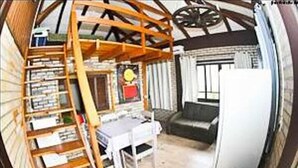 A compact room with a loft bed, a small table, and a couch. - Pousada Vento & Cia (Laguna)