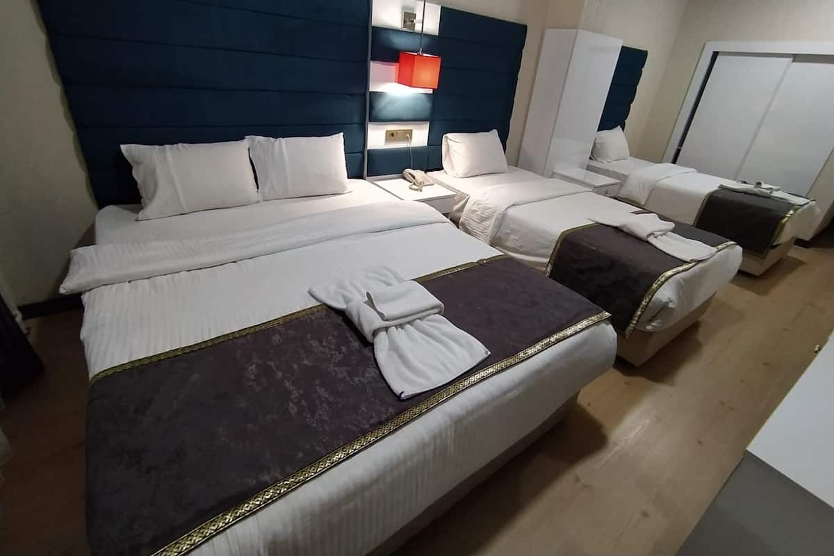 A hotel room with two beds, a nightstand, a bedside table, a mirror, and a wardrobe.