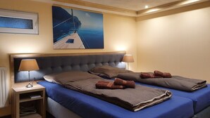 Ein Hotelzimmer mit einem großen Bett, zwei Nachttischen, einem Kopfteil und einem Bild von einem Boot an einem Steg.