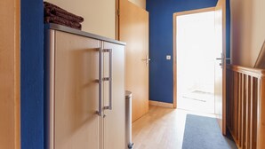 Ein Flur mit einem Schrank, einem Mülleimer und einer blauen Matte, die zu einer Tür führt.