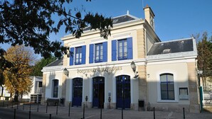 A building with a classic architectural style, featuring a prominent entrance with blue shutters and a sign reading "FONTEINAY-AUX-ROSES".