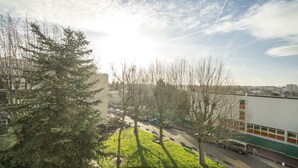 A view of a building with a parking area, trees, and a clear sky.