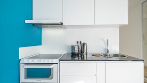 A modern kitchen with white cabinetry, a built-in oven, a sink, and a coffee maker.