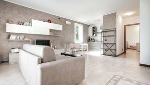 Un salon moderne avec un canapé, une cheminée, un coin repas et une cuisine en arrière-plan.