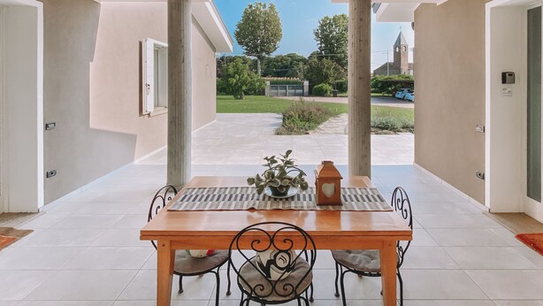 Un coin repas avec une table et des chaises, une plante en pot et une lanterne.