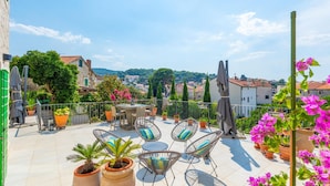 A terrace with outdoor seating, potted plants, and a view of the surrounding buildings. - Beautiful home in Postira (Postira)