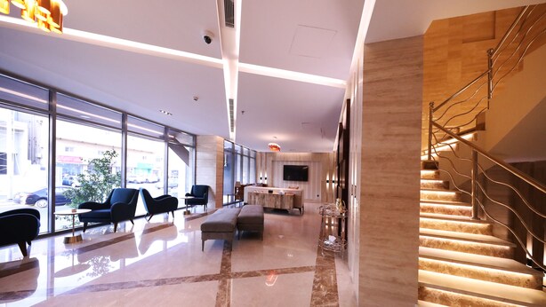 A spacious lobby with a marble floor, modern furniture, a staircase, and large windows offering a view of the outside. - EVA Hotel (Jeddah)
