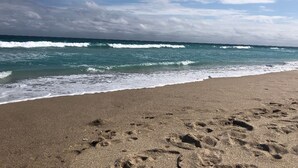 Ein Strand mit Fußspuren im Sand und brechenden Wellen.